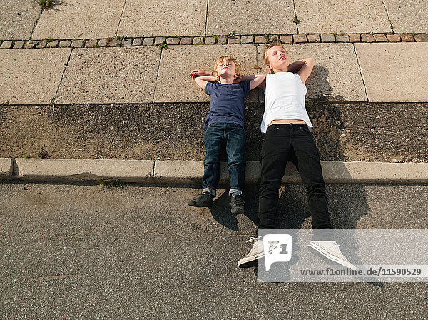 Brothers lying together on sidewalk