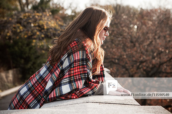 Girl with plaid blanket looking over wall