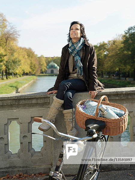 Frau sitzt im Herbst auf der Flussbrücke