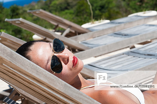 Junge Frau mit Sonnenbrille auf Liegestuhl