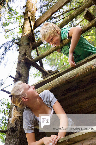 Junge und Mädchen klettern auf Baumhaus