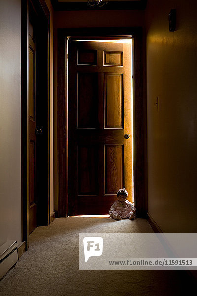 Puppe sitzend in der Tür im Flur