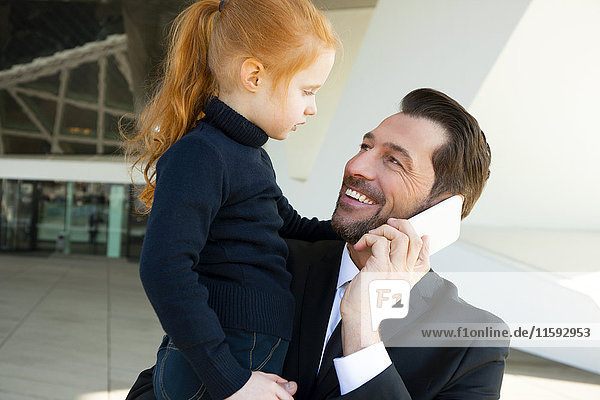 Lächelnder Geschäftsmann am Telefon mit Tochter