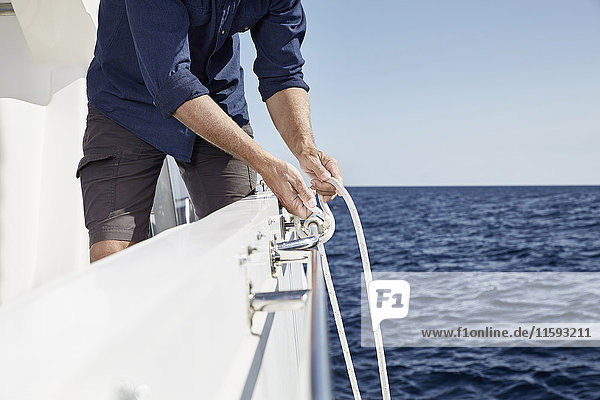 Man on motor yacht tying a knot  partial view