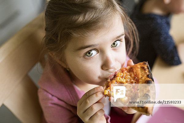 Kleines Mädchen zu Hause isst Pizzastückchen