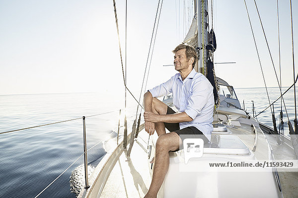 Lächelnder reifer Mann entspannt auf seinem Segelboot