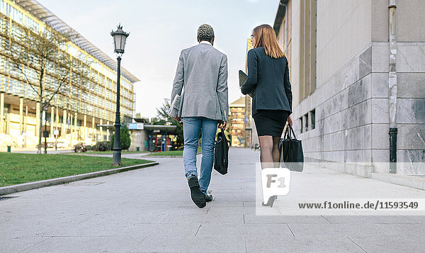 Ein junger Geschäftsmann und eine junge Frau  die in der Stadt spazieren gehen.
