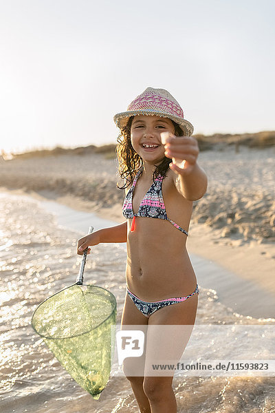 Spanien,  Menorca,  Porträt eines glücklichen Mädchens mit einem Dip-Netz am Strand