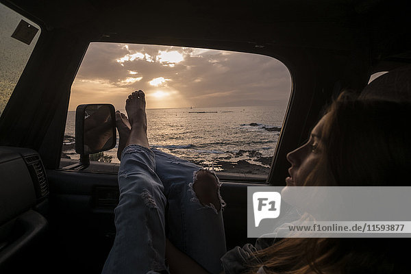 Frau bei Sonnenuntergang im Auto sitzend