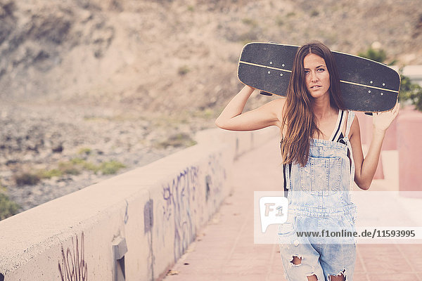 Junge Frau mit Skateboard auf den Schultern