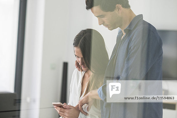 Young couple in love looking at cell phone at home