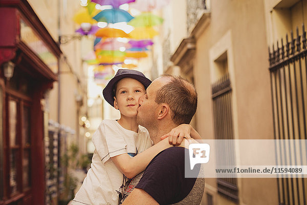 France  Languedoc  Beziers  father kissing son with colorful umbrellas in background