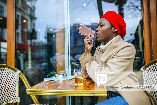 Young woman in Paris sitting in cafe and leaving a voice message