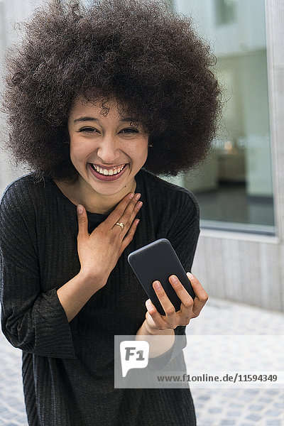 Porträt einer lachenden jungen Frau mit Smartphone