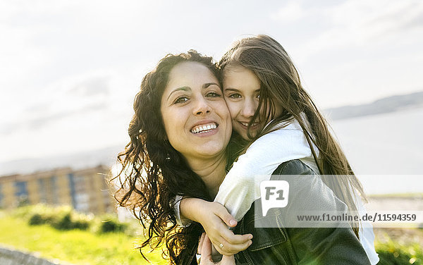 Portrait of happy mother carrying daughter outdoors