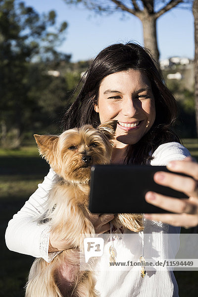 Fröhliche junge Frau nimmt Selfie mit ihrem Hund mit