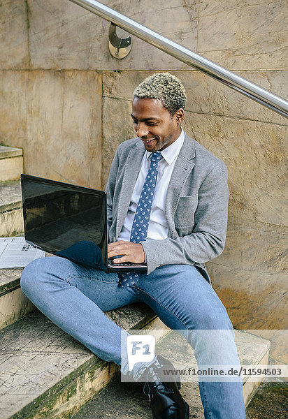 businessman sitting on stairs  using laptop