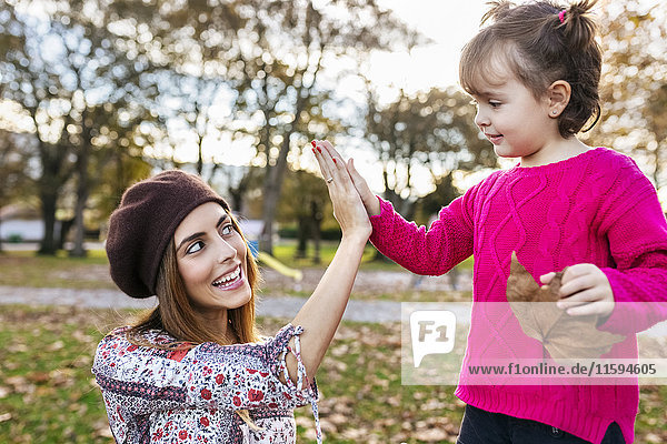 Mutter und kleine Tochter High Fiving im Herbstpark