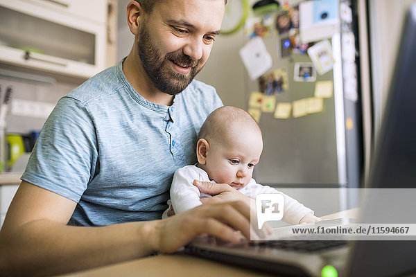 Vater mit Baby-Sohn mit Laptop zu Hause