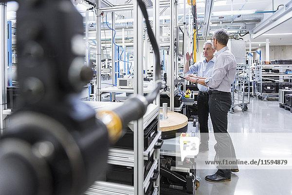 Two businessmen in modern factory hall talking