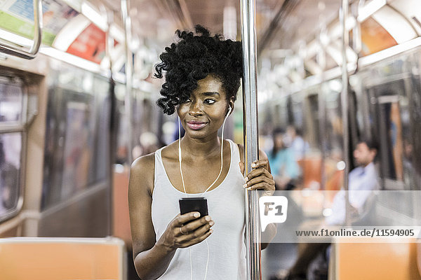 USA  New York City  Manhattan  Porträt einer entspannten Frau mit Handy in der U-Bahn