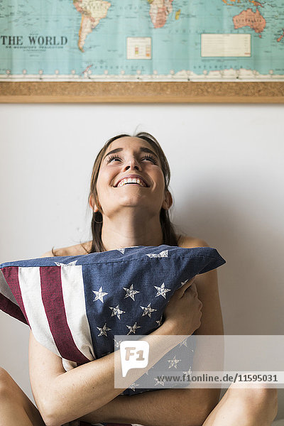 Lächelnde junge Frau mit US-Kissen unter der Weltkarte