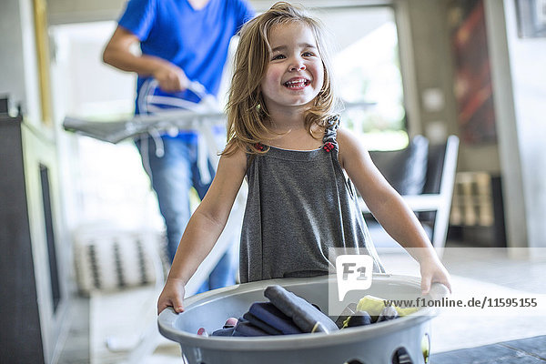 Glückliches kleines Mädchen mit Wäschekorb