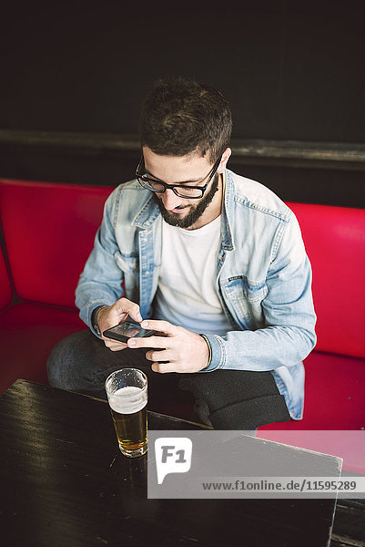 Junger Mann sitzend in einer Kneipe SMS