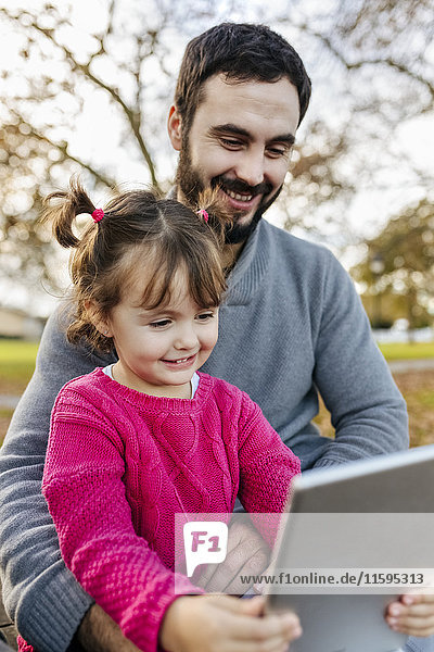 Vater und kleine Tochter nehmen Selfie mit Tablette im Herbstpark