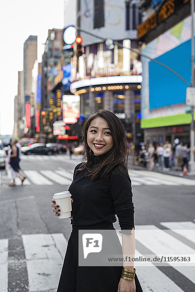 USA  New York City  Manhattan  fröhliche junge Frau mit Kaffee auf die Straße gehen