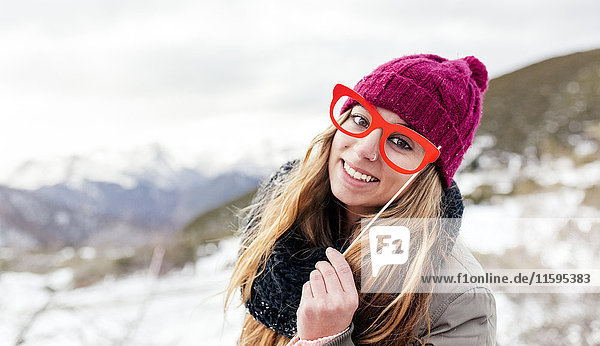 Junge Frau mit gefälschter Brille amüsiert sich in den verschneiten Bergen