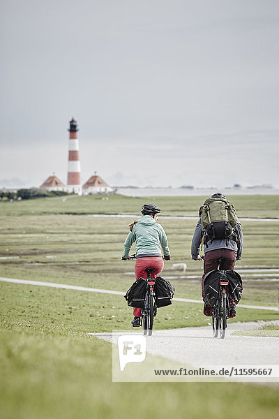 Germany  Schleswig-Holstein  Eiderstedt  couple riding bicycle near Westerheversand Lighthouse