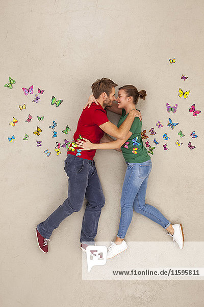 Junges Paar küsst sich inmitten von Schmetterlingen