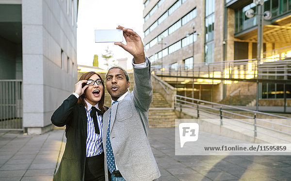 Junger Geschäftsmann und Frau beim Fotografieren von Smartphones