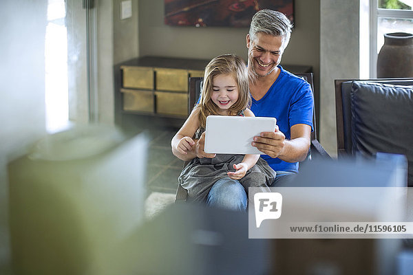 Vater und Tochter schauen auf digitales Tablett
