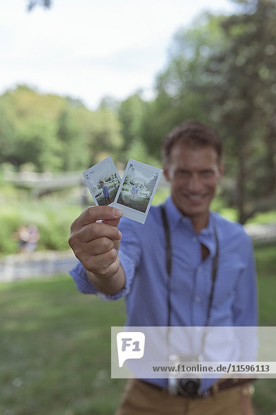 Man showing instant photos in a park