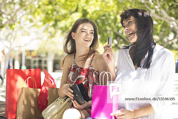 Glückliche Mutter und Tochter mit Einkaufstaschen und Kreditkarte in der Stadt