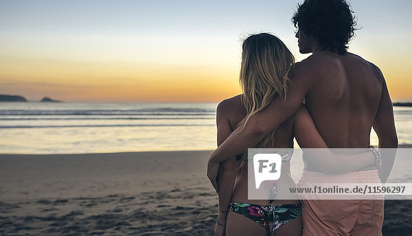 Junges Paar beobachtet den Sonnenuntergang am Strand