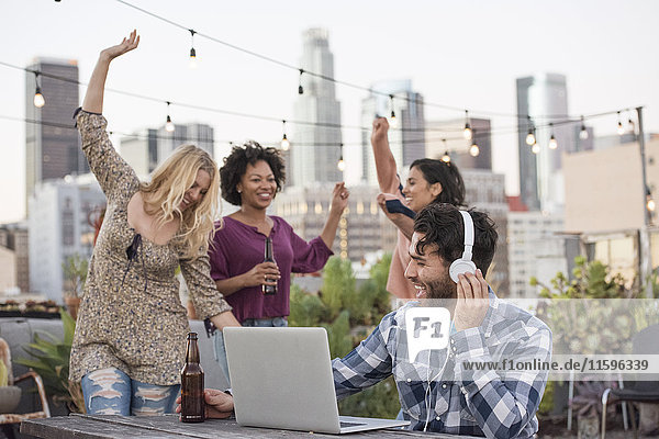 Leute tanzen auf der Dachparty  mit DJ mit Laptop