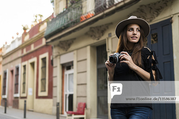 Porträt einer lächelnden jungen Frau mit Kamera im Freien