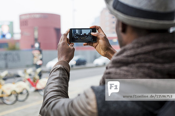 Back view of man taking photo with smartphone