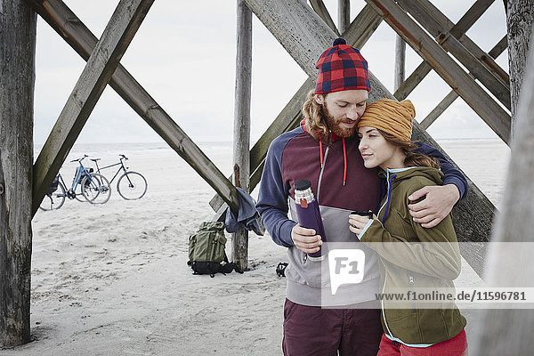 Deutschland  Schleswig-Holstein  St. Peter-Ording  Paar auf einer Fahrradtour mit Pause am Strand