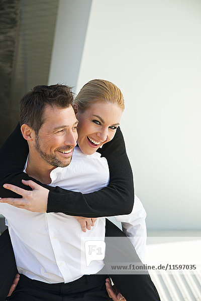 Portrait eines glücklichen Geschäftsmannes mit Huckepack-Frau