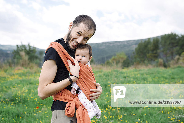 Father carrying baby girl outdoors in a baby sling