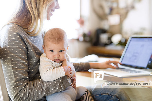 Mutter mit Baby zu Hause mit Laptop