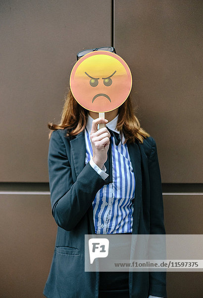 Woman hiding face behind emoji mask