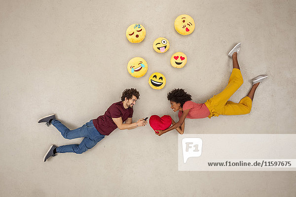 Glückliche Paare,  die auf ihren Smartphones SMS schreiben und Emojies verschicken.
