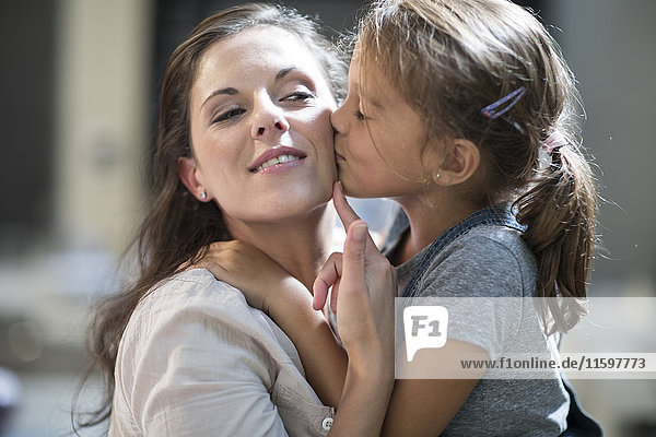Mutter und Tochter küssen und umarmend