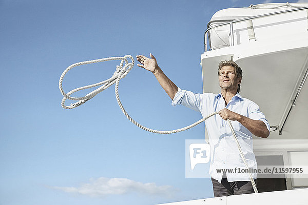 Mature man on motor yacht throwing rope