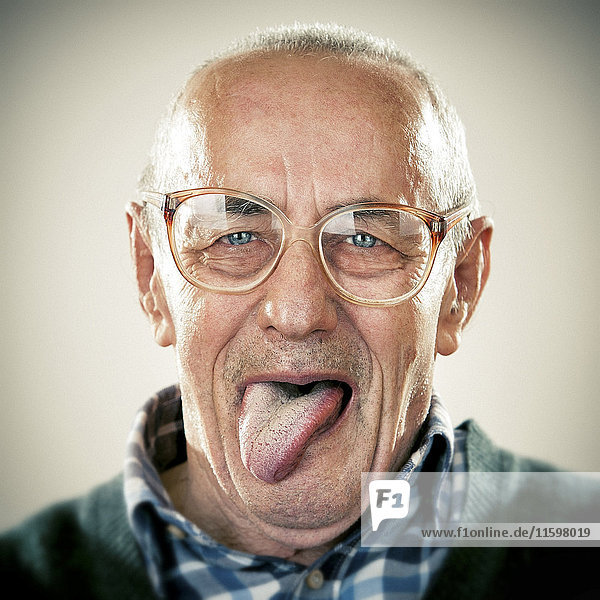 Porträt eines älteren Mannes  der seine Zunge herausstreckt.